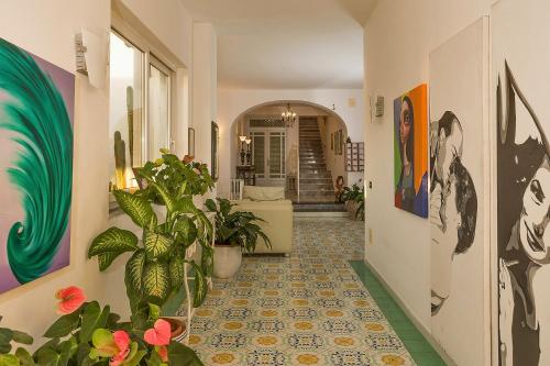 a hallway with plants and paintings on the walls at Hotel Villa Maria in Ischia