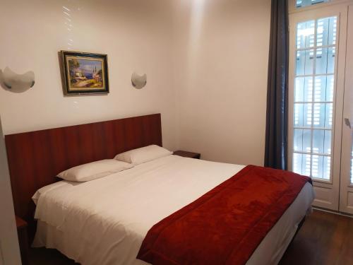 a bedroom with a bed and a large window at Hotel Le Postillon in Pau