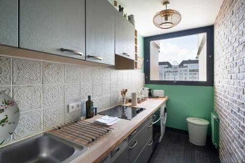 une petite cuisine avec un évier et une fenêtre dans l'établissement Angèle by Cocoonr, à Rennes