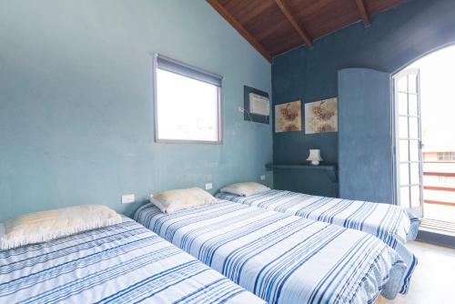 two beds in a room with blue walls at Mandala Maresias in Maresias