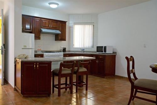 a kitchen with wooden cabinets and a counter with bar stools at Best Western Saltillo in Saltillo