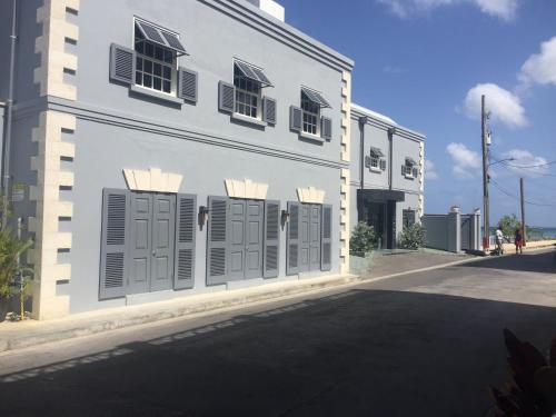 a white building with gray shutters on a street at Heywoods Villa in Saint Peter