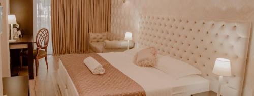 a bedroom with a large white bed and a chair at Green House Hotel & Restaurant in Tirana