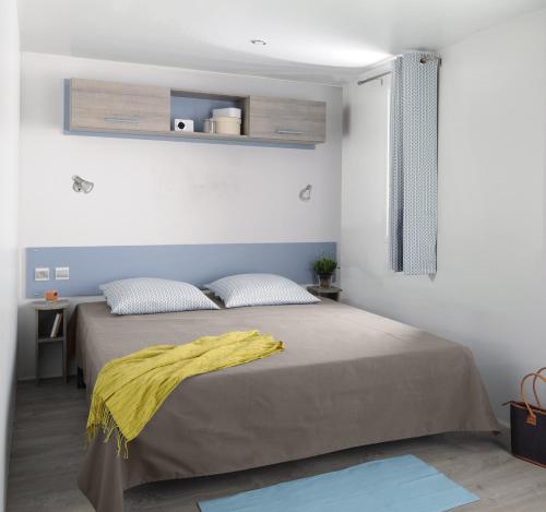 ein Schlafzimmer mit einem Bett mit einer gelben Decke darauf in der Unterkunft Camping Campo Di Liccia - Maeva in Bonifacio