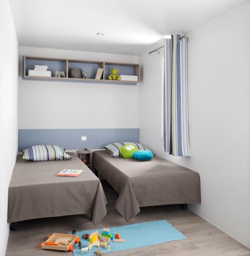 een kamer met twee bedden en een speelset op de vloer bij Camping Campo Di Liccia - Maeva in Bonifacio