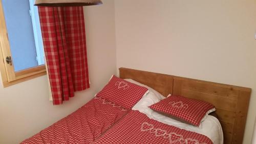 - un lit avec 2 oreillers rouges dans l'établissement appart chalet hameau des rennes - luxe -pied des pistes, à Vars