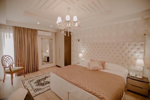 a white bedroom with a large bed and a chandelier at Green House Hotel & Restaurant in Tirana
