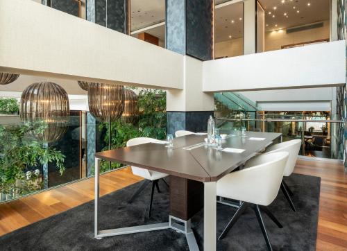 a dining room with a wooden table and white chairs at Ilunion Valencia 4 in Valencia