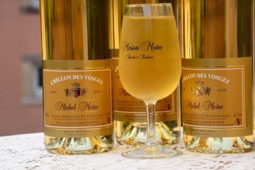 a glass of wine sitting next to three bottles of champagne at Les Charmois - Spa privatif en supplément et sur un autre site in Bains-les-Bains