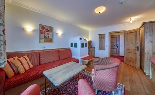 a living room with a red couch and a table at Bauernhof Hotel Oberschwarzach in Saalbach Hinterglemm
