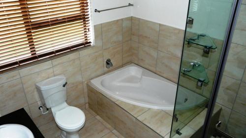 a bathroom with a tub and a toilet and a shower at Oyster Catcher Stay And Explore in Cape St Francis