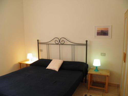 a bedroom with a black bed with two lamps on tables at MaremMare Tuscany Apartments in Principina a Mare