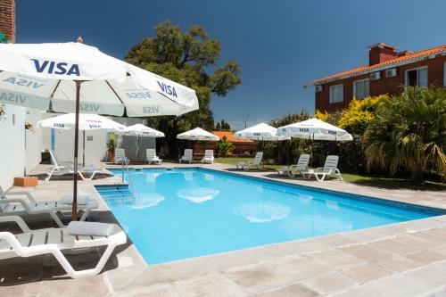 a swimming pool with chairs and umbrellas at Gran Hotel Fray Bentos in Fray Bentos