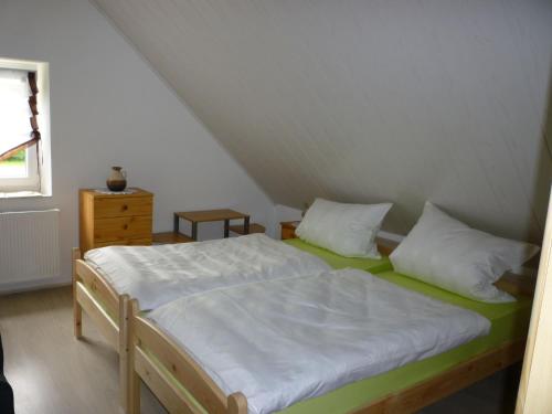1 dormitorio con 1 cama con sábanas y almohadas blancas en Gasthaus - Pension Am Buchberg, en Mönchsdeggingen