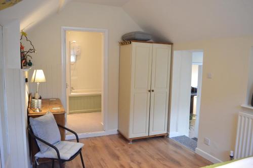 a room with a chair and a cabinet and a desk at Halfway House in Great Malvern