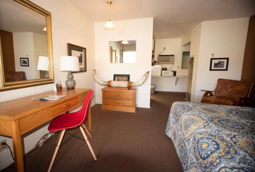 Schlafzimmer mit einem Schreibtisch, einem Bett und einem Spiegel in der Unterkunft Raton Pass Motor Inn in Raton