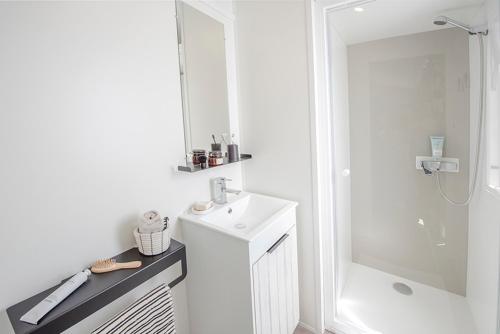 La salle de bains blanche est pourvue d'un lavabo et d'une douche. dans l'établissement Camping St Tro’Park **** - Maeva, à Saint-Trojan-les-Bains
