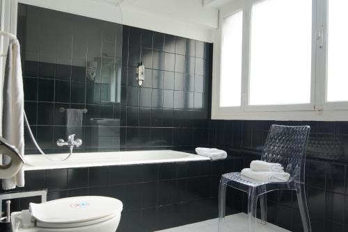 a bathroom with a tub and a toilet and a chair at ATH hôtel Athénée in Cannes