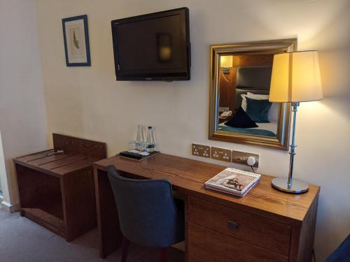 una camera con scrivania, lampada e specchio di Cotswold Lodge Hotel a Oxford