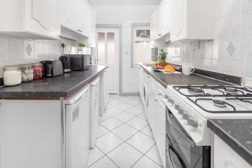 a white kitchen with white cabinets and a stove at Superb Spacious House For Contractors & Families & Private Parking By Liverpool Short Stay in Liverpool