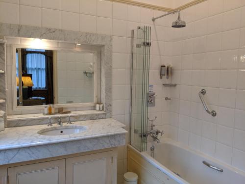 a bathroom with a shower, sink, and mirror at Cotswold Lodge Hotel in Oxford