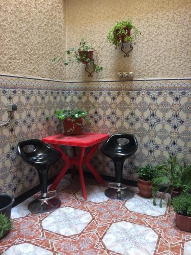 a red table with two black stools in a room at Senhaja Suite in Targuist