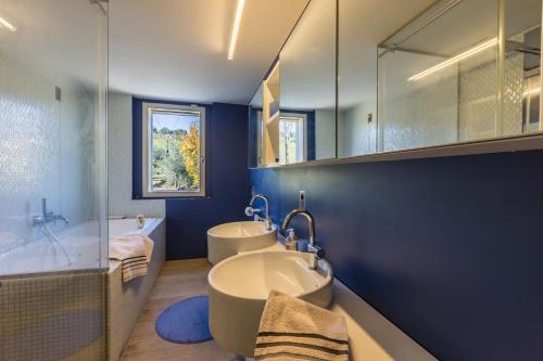 a blue bathroom with two sinks and a tub and a tub at Villa Aurora in Trecastelli