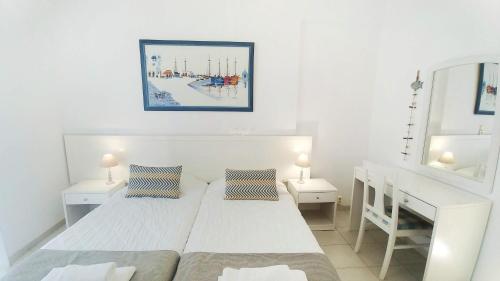 a white bedroom with two beds and a mirror at Hotel Marinero in Naousa