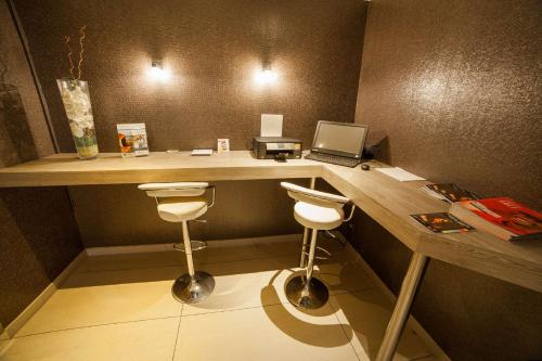 a room with a desk with a laptop and two stools at Best Western Plus Evreux Palais Des Congrès in Évreux