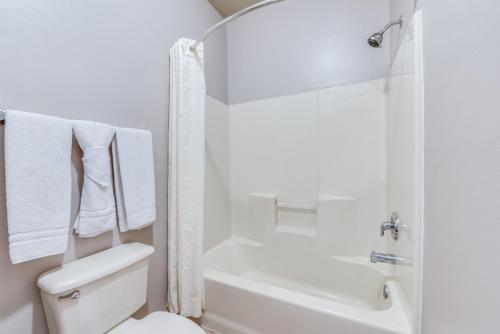 a white bathroom with a toilet and a bath tub at Lone Star Inn - San Benito in San Benito
