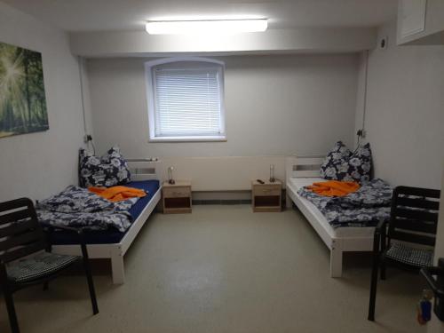 two beds in a room with two chairs and a window at Monteurwohnung Zentrum in Zerbst