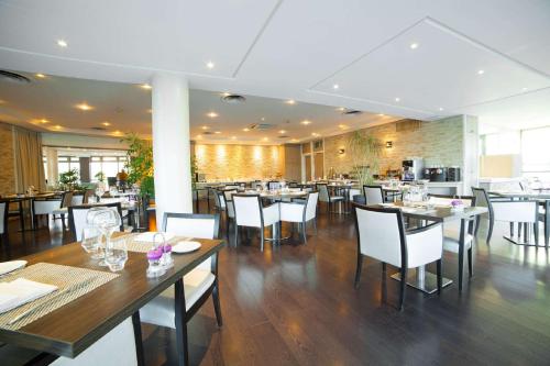 a restaurant with wooden tables and white chairs at Best Western Plus Evreux Palais Des Congrès in Évreux