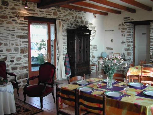 a dining room with a table and a stone wall at Le Domaine de Rugornou Vras in Brasparts