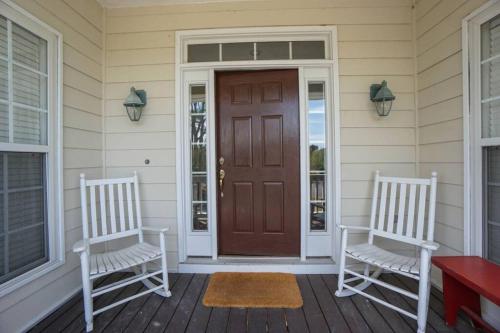 two chairs on the front porch of a house with a door at Paradise on Nautical Watch **Pool Just Steps Away** in Harbor Island