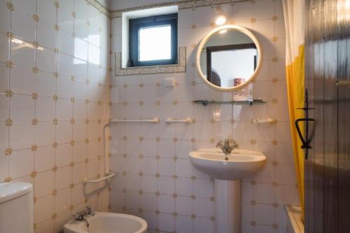 een badkamer met een wastafel, een toilet en een spiegel bij Pedras Del Rei I in Tavira