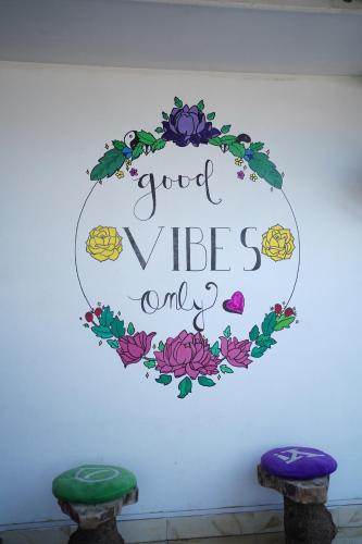 a sign that says good vibes only on a wall with two stools at North Centre in Cochin