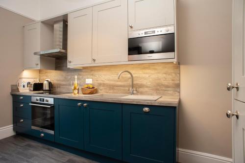 una cocina con armarios azules y fregadero en Amadeus Apartments, en Douglas