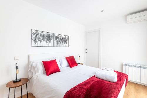 1 dormitorio con cama blanca y almohadas rojas en Cituspace Arturo Soria en Madrid