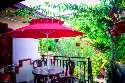a table with a red umbrella on a patio at Tissa Rainbow Guest & Yala in Tissamaharama