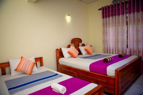 Habitación con 2 camas individuales en color púrpura y blanco en Tissa Rainbow Guest & Yala, en Tissamaharama