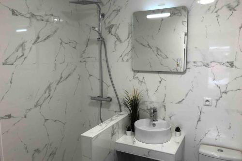 La salle de bains en marbre blanc est pourvue d'un lavabo et d'un miroir. dans l'établissement FRATELLINI 3 Bedroom bright and design, à Saint-Ouen