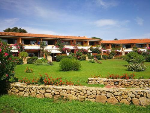 a building with a garden with flowers and a stone wall at Residenze Coda Cavallo in San Teodoro
