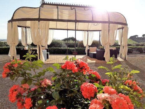 a gazebo with red flowers in a garden at Villa Curina Resort in Castelnuovo Berardenga