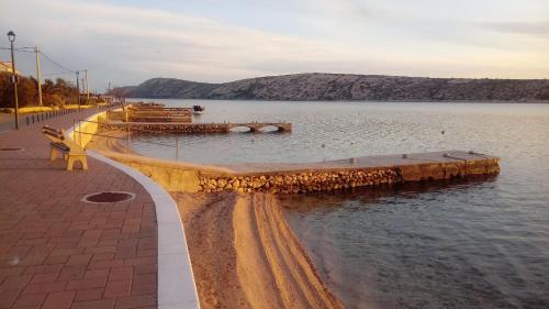 a bench sitting next to a body of water at Apartmani Krunić in Barbat na Rabu