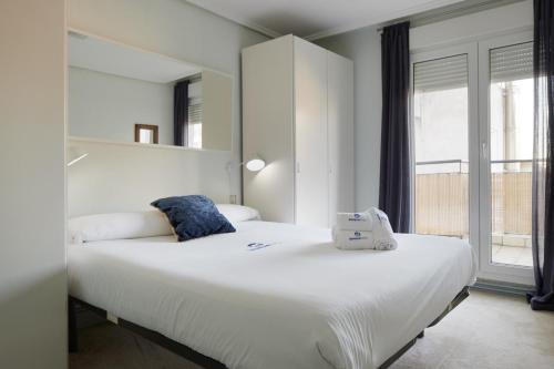 a white bedroom with two beds and a window at Marrubi - Basque Stay in San Sebastián