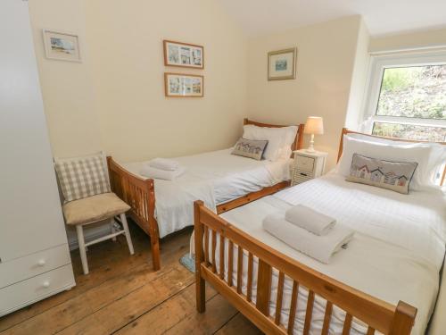 a twin bedroom with two beds and a chair at Ty Gwyn in Aberdyfi