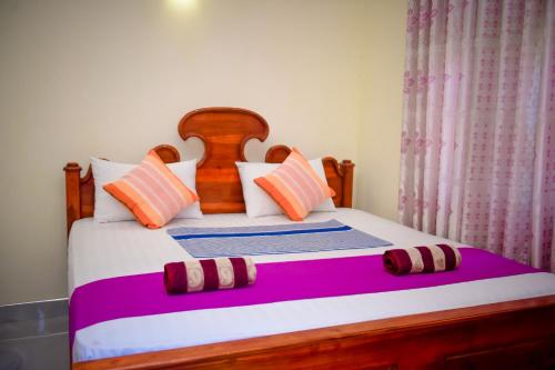 a bedroom with a large bed with colorful pillows at Tissa Rainbow Guest & Yala in Tissamaharama