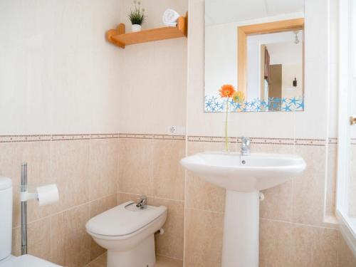 a bathroom with a sink and a toilet and a mirror at Apartamentos Doña Maria in Alcossebre