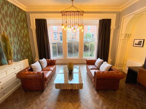 a living room with leather furniture and a chandelier at The Deakin at Claremont Serviced Apartments in Leeds