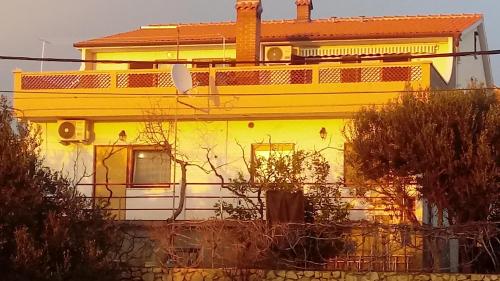 a yellow and white house with trees in front of it at Apartmani Krunić in Barbat na Rabu